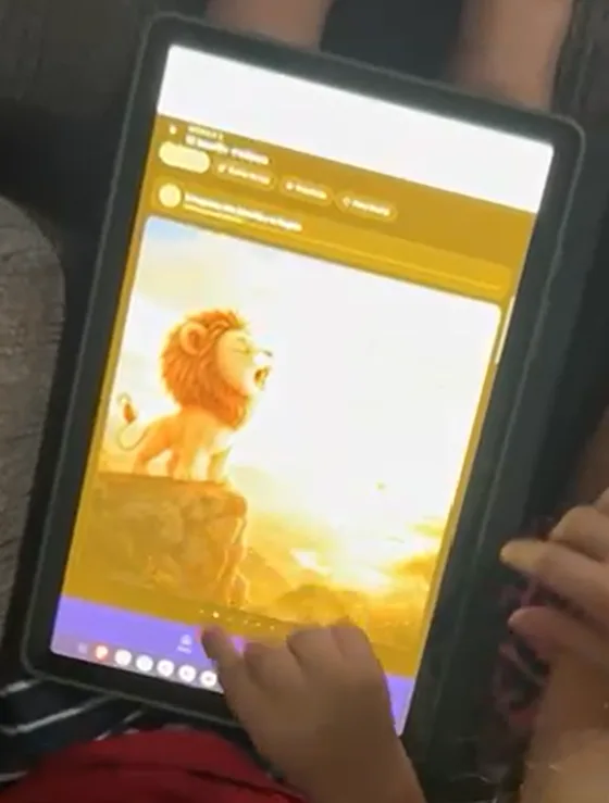 Un niño de 2 años toca la tablet con el cuento del león dentro de la app